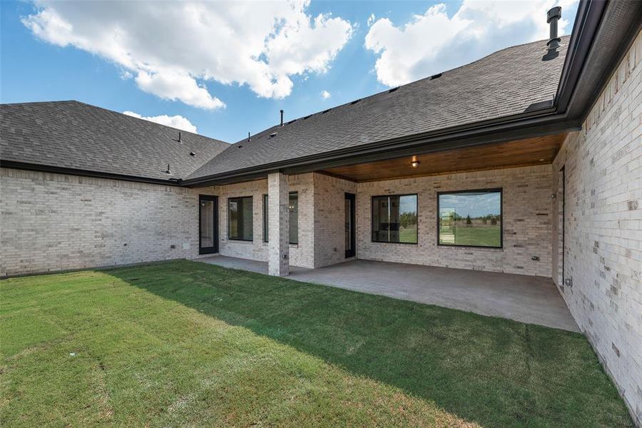 Back of house with a patio area, brick siding, and roof with shingles