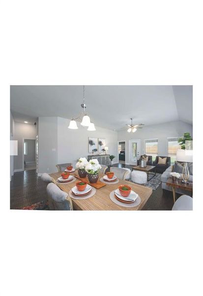 Dining room featuring ceiling fan with notable chandelier, vaulted ceiling, and dark hardwood / wood-style flooring