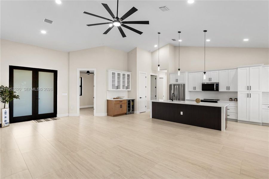 IMPACT-RESISTANT DOUBLE DOORS lead into WELCOMING LIVING ROOM w/ 12-ft VAULTED CEILING & SLIDING DOORS TO LANAI.