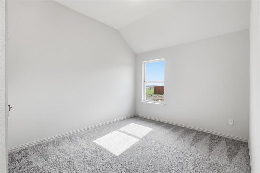 Room with vaulted ceiling, light gray carpet flooring, and a single window Room with vaulted ceiling, light gray carpet flooring, and a single window