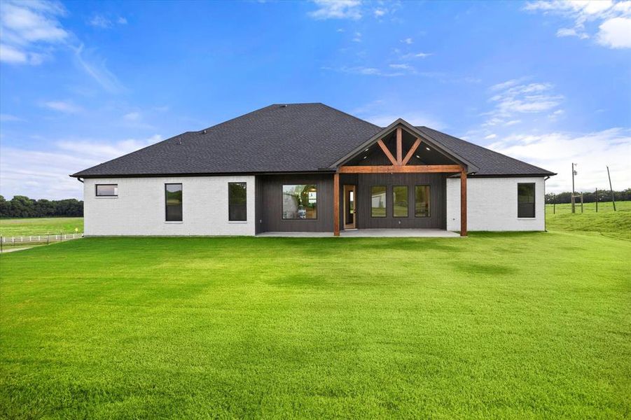 Back of property with a patio, a lawn, brick siding, and roof with shingles Back of property with a patio, a lawn, brick siding, and roof with shingles
