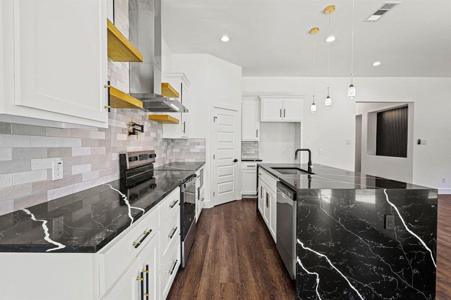 Kitchen with a kitchen island with sink, stainless steel appliances, a sink, and decorative light fixtures