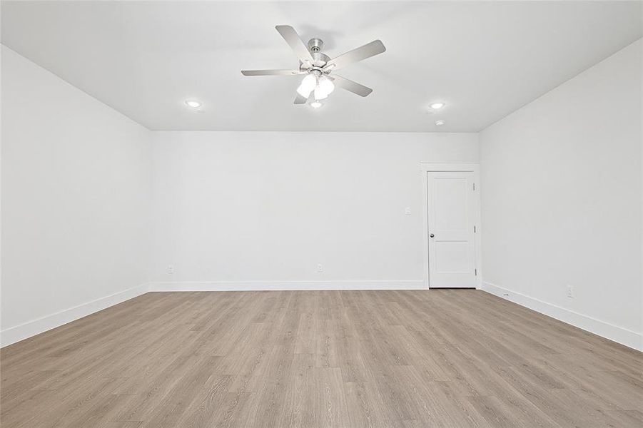 The spacious room features light-colored flooring, white walls, and a ceiling fan with integrated lighting