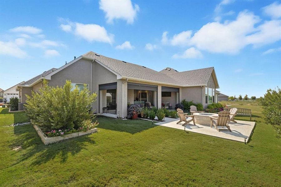 Back of property featuring a fire pit, a patio, stucco siding, and a yard