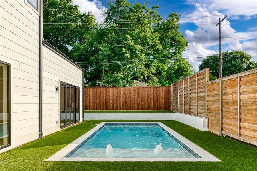 View of swimming pool with pool water feature and a lawn