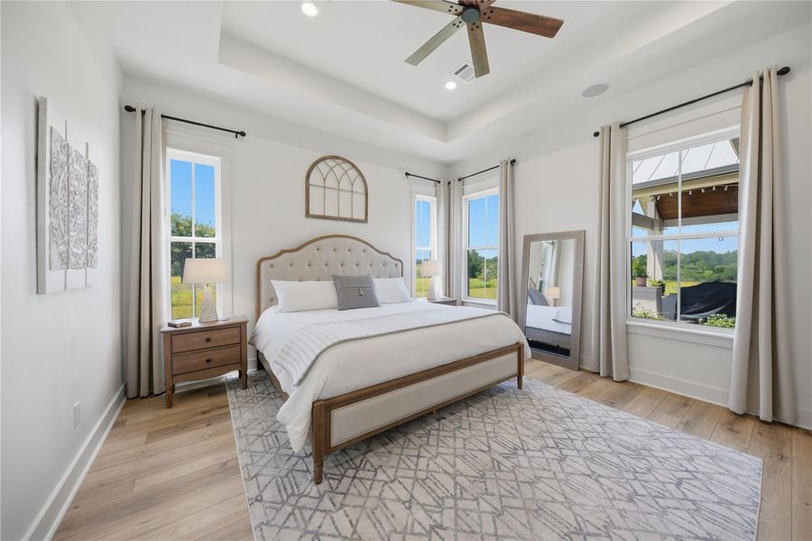 An inviting sleeping quarter with high ceilings and wide windows that let in natural illumination and views of the outdoors.