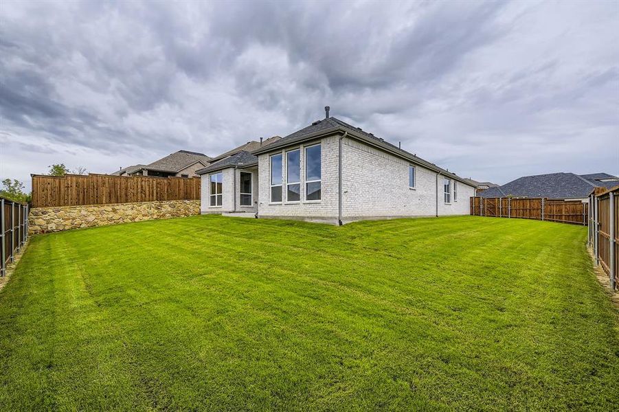 Back of house featuring a fenced backyard and brick siding