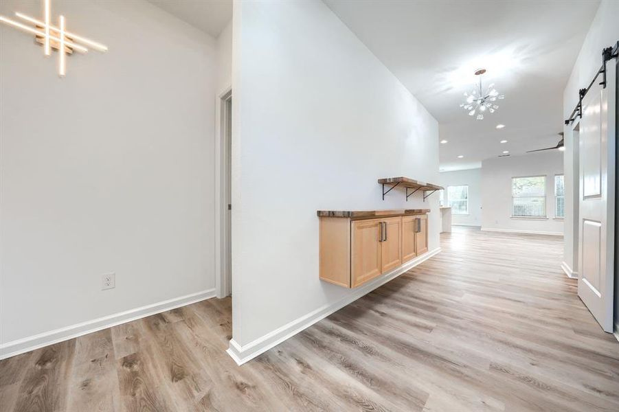 Hallway featuring a barn door, a chandelier, light wood finished floors, and recessed lighting