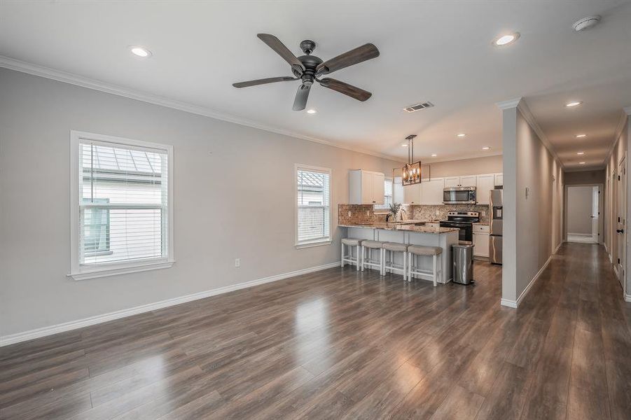 Living area featuring crown molding, dark wood finished floors, ceiling fan, recessed lighting, and a chandelier Living area featuring crown molding, dark wood finished floors, ceiling fan, recessed lighting, and a chandelier