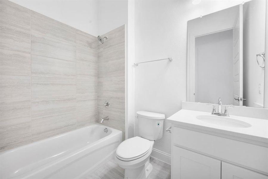 Full bathroom with toilet, tiled shower / bath combo, and vanity