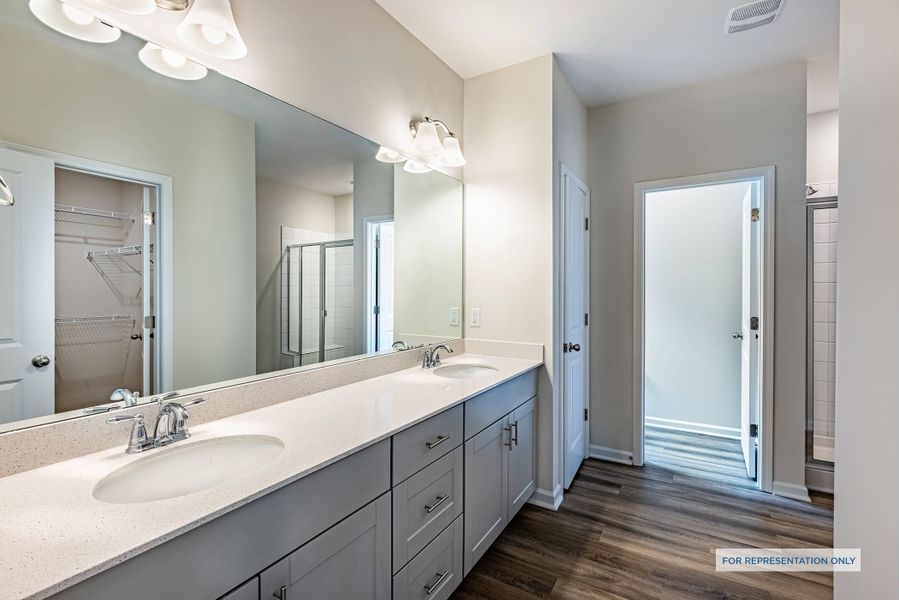 Representative photo of the Melton plan owner's suite bathroom with dual vanities and walk-in shower.