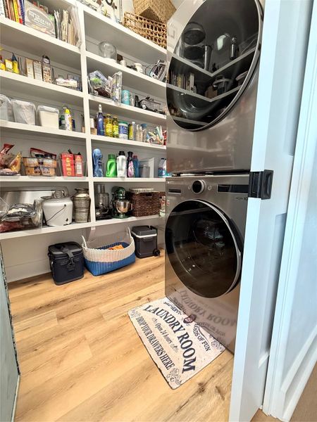 This photo shows a well-organized laundry room and pantry with a stacked washer and dryer. It features ample shelving for storage.
