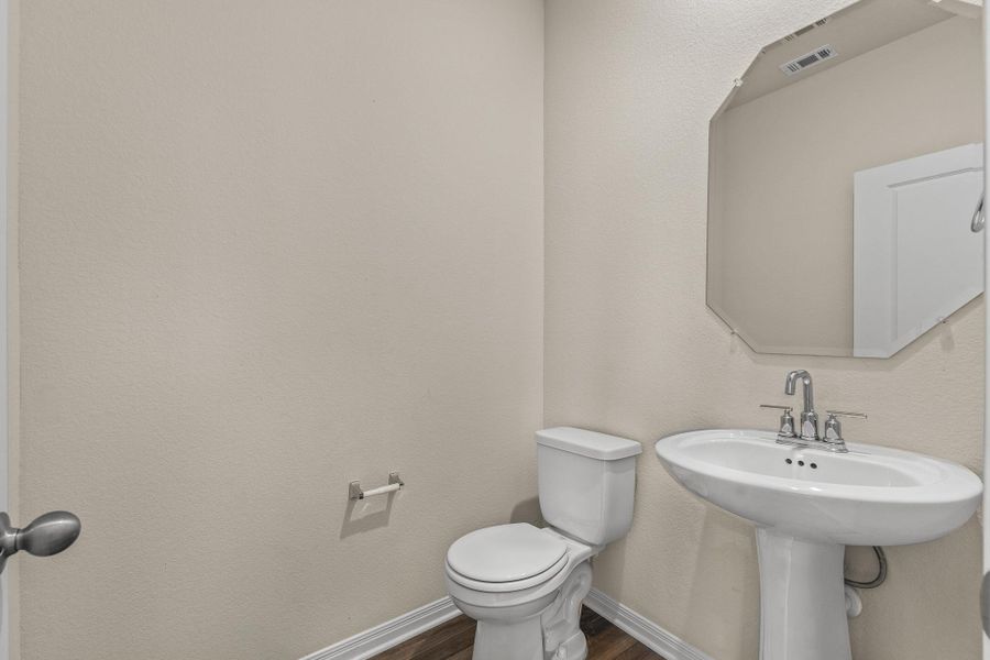 Half bath with a textured wall and dark wood finished floors Half bath with a textured wall and dark wood finished floors