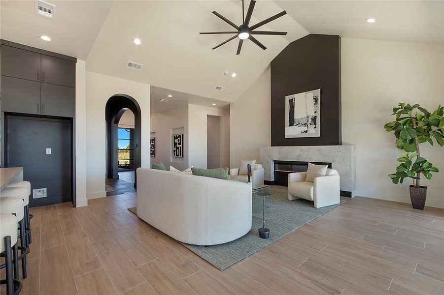 Living room featuring wood tiled floors, arched walkways, high vaulted ceiling, ceiling fan, and recessed lighting Living room featuring wood tiled floors, arched walkways, high vaulted ceiling, ceiling fan, and recessed lighting