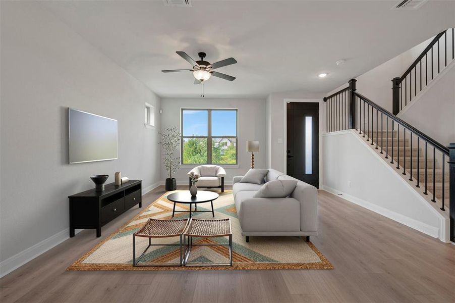 Open-concept living area featuring wood-finish flooring, a contemporary ceiling fan, and a large window providing ample natural light