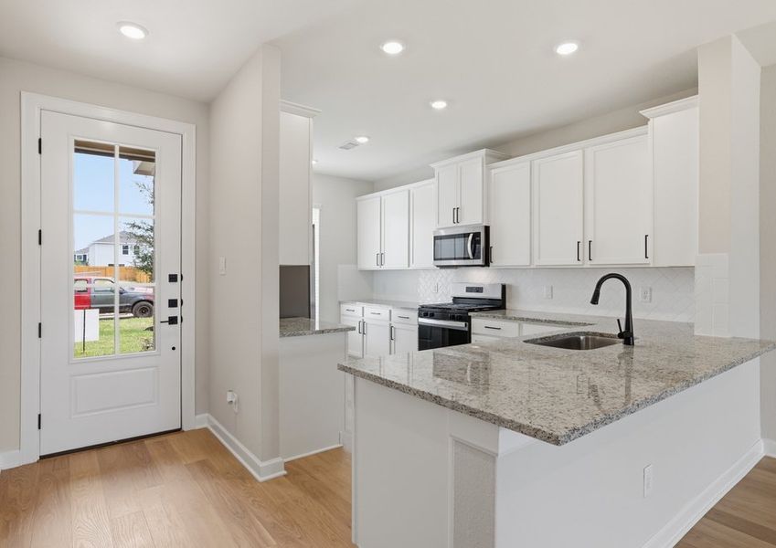 Kitchen featuring a granite island, white cabinetry, and a glass door leading to the dining area.