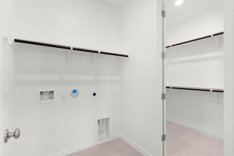 Washroom featuring hookup for a gas dryer, electric dryer hookup, washer hookup, baseboards, and light tile patterned floors