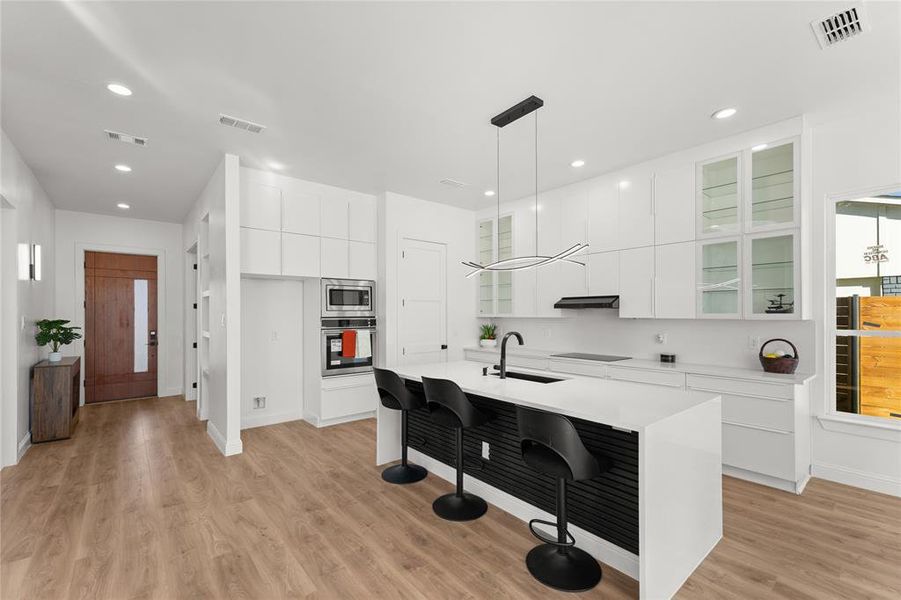 Kitchen with glass insert cabinets, white cabinets, a breakfast bar area, and stainless steel appliances