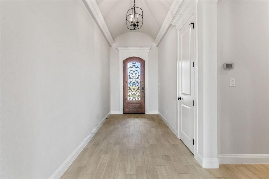 Entrance foyer featuring vaulted ceiling, light wood-style flooring, and a chandelier