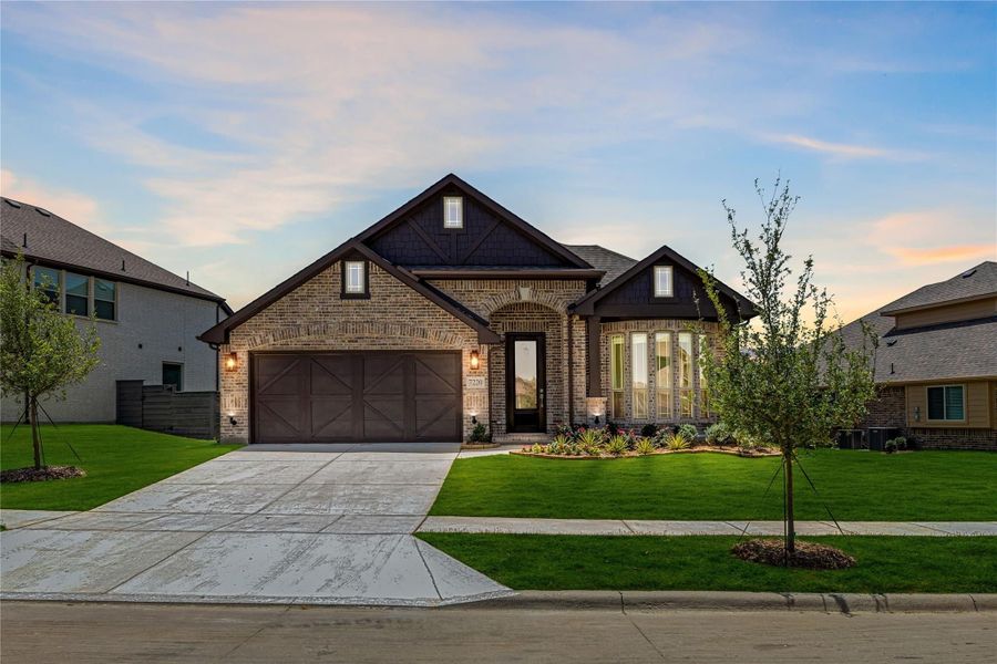 Single-story brick home with dark trim, two-car garage, and landscaped front yard Single-story brick home with dark trim, two-car garage, and landscaped front yard