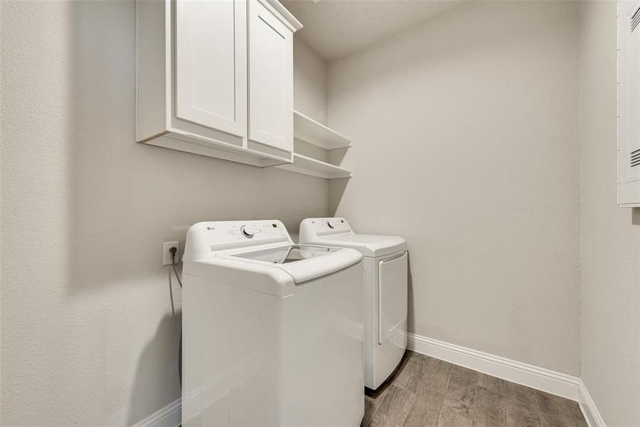 Washroom featuring cabinet space, light wood-style flooring, and independent washer and dryer
