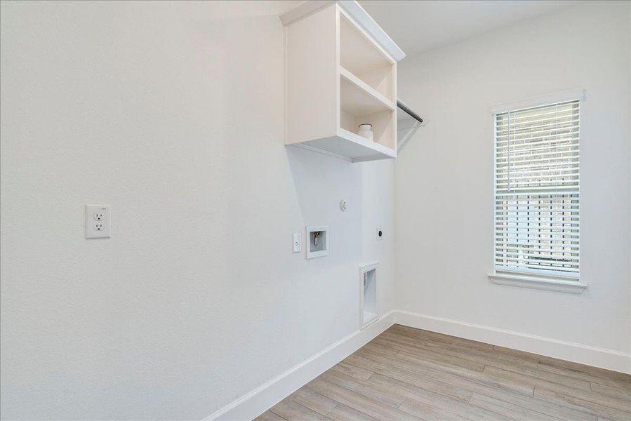 Dedicated utility area featuring built-in shelving, a clothes hanging rod, and a window for natural light