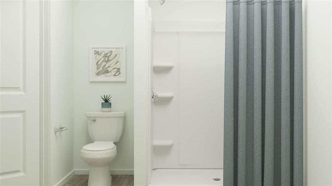 Bathroom featuring a shower with shower curtain, hardwood / wood-style flooring, and toilet