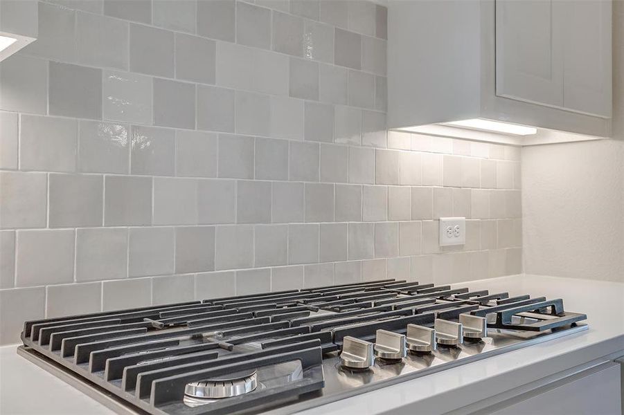 Room details with stainless steel gas stovetop and decorative backsplash