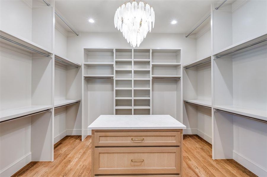 Walk in closet featuring light wood-style flooring and a chandelier Walk in closet featuring light wood-style flooring and a chandelier