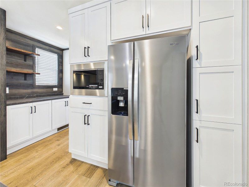 Kitchen – Range Wall (Angle) – Clean, modern design with ample counter space, upper cabinetry, and stainless steel appliances.