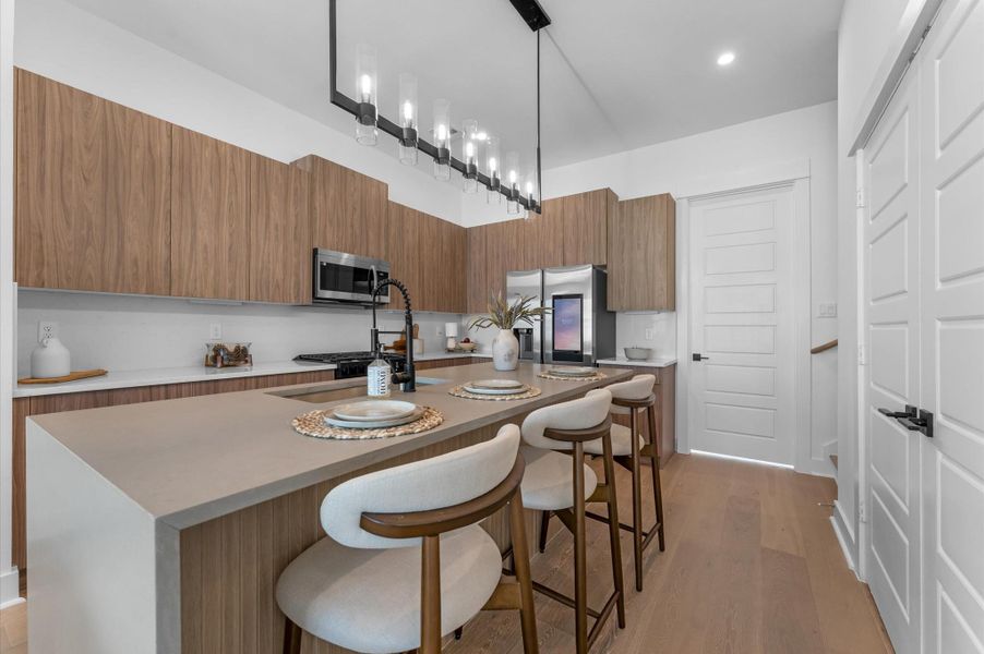 The heart of the second-floor open-concept living, dining, and kitchen, this spacious kitchen island features sleek modern finishes, including a one-sided cascade quartz countertop, a farmhouse sink, and stylish pendant lighting, with a built-in seating area perfect for casual breakfasts or chatting with family and frien