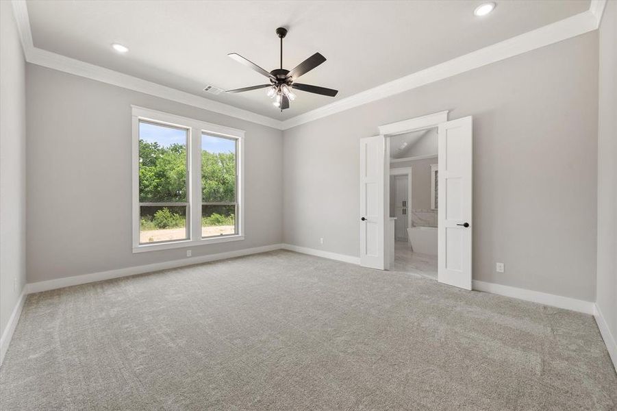 Spacious room featuring light gray carpet, multiple windows, a ceiling fan, recessed lighting, and crown molding