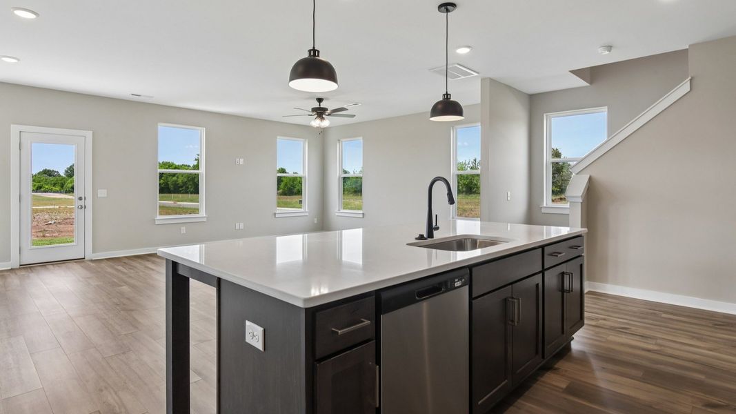Kitchen with dark cabinetry, quartz countertops, and view of gathering room Kitchen with dark cabinetry, quartz countertops, and view of gathering room