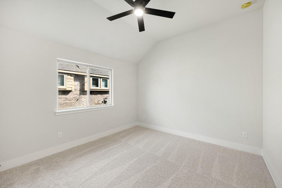 Empty bedroom with vaulted ceiling, black ceiling fan, carpet flooring, and single window
