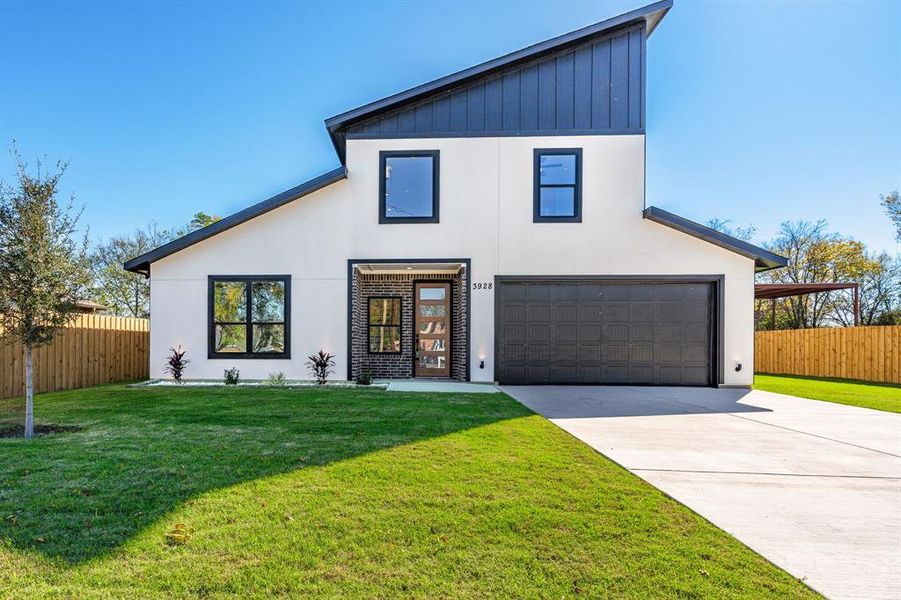 View of front of property with a garage and a front lawn