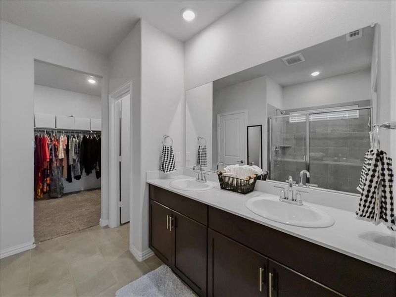 Bathroom with tile patterned flooring, walk in shower, and double vanity