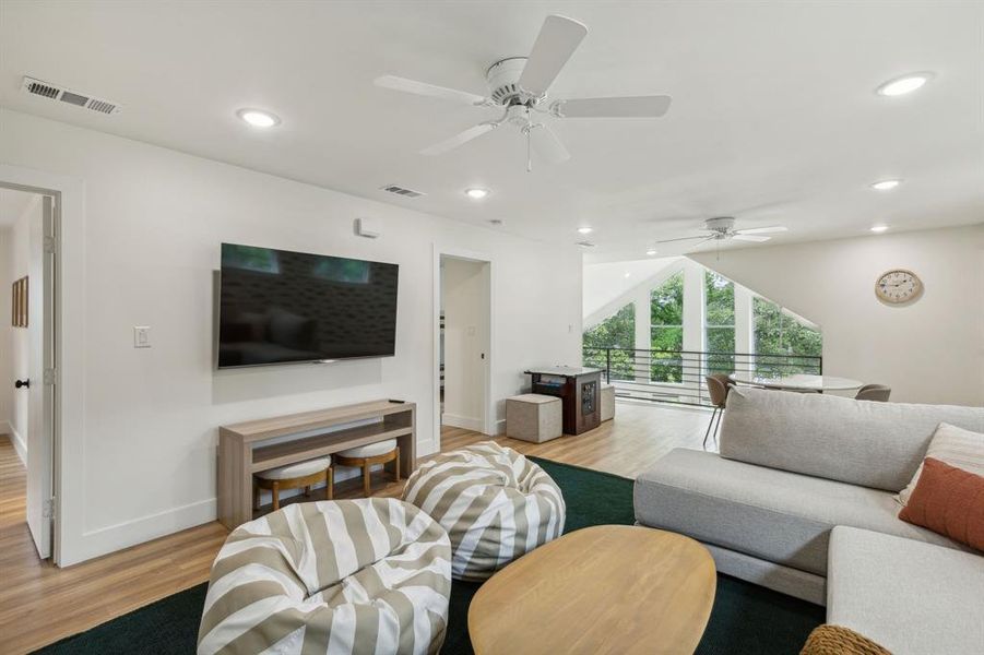 Living room with ceiling fan, light wood-type flooring, and lofted ceiling