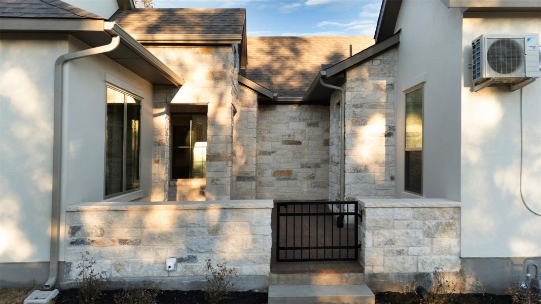 Entrance to property with stone siding, roof with shingles, and stucco siding