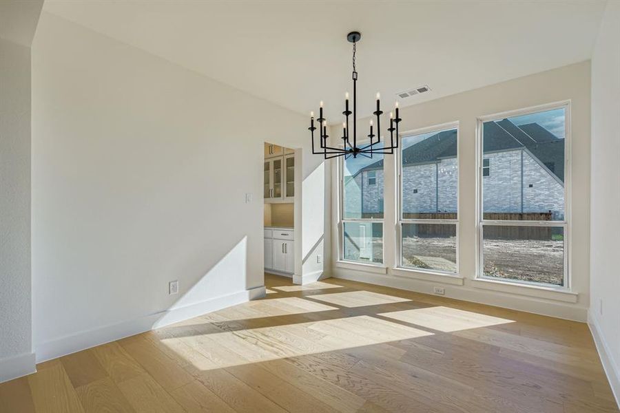 Unfurnished dining area featuring light wood-type flooring and a chandelier Unfurnished dining area featuring light wood-type flooring and a chandelier