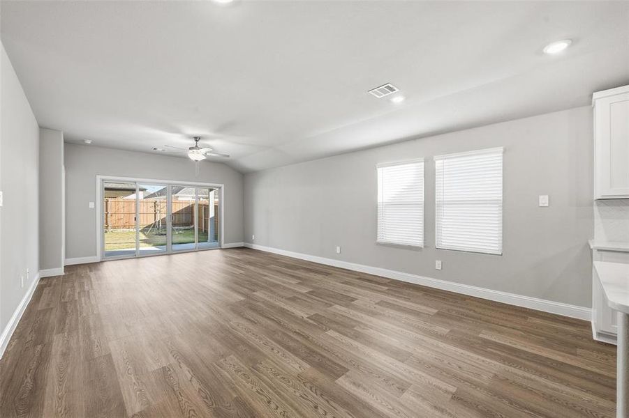 Unfurnished living room with wood finished floors, vaulted ceiling, ceiling fan, and recessed lighting