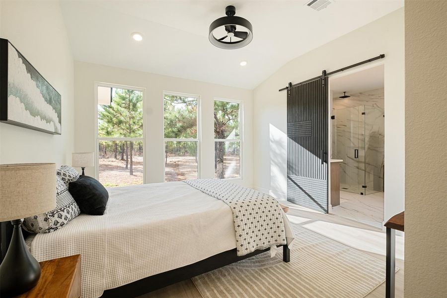 Bedroom featuring a barn door, vaulted ceiling, ensuite bath, and recessed lighting