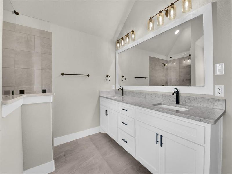 Full bathroom featuring lofted ceiling, walk in shower, double vanity, and light tile patterned flooring Full bathroom featuring lofted ceiling, walk in shower, double vanity, and light tile patterned flooring