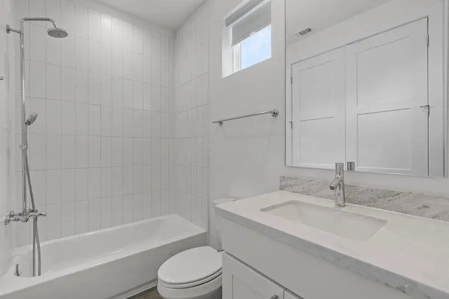 Sleek vertical tiling frames the shower-tub combination adjacent to a stone-counter vanity. Sleek vertical tiling frames the shower-tub combination adjacent to a stone-counter vanity.