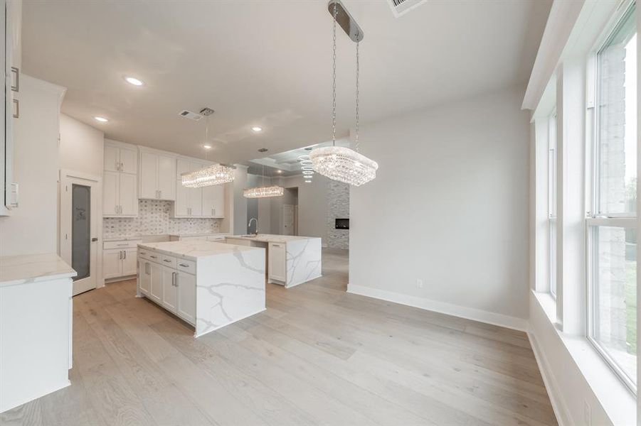 Kitchen featuring light stone counters, decorative backsplash, light wood finished floors, pendant lighting, and recessed lighting