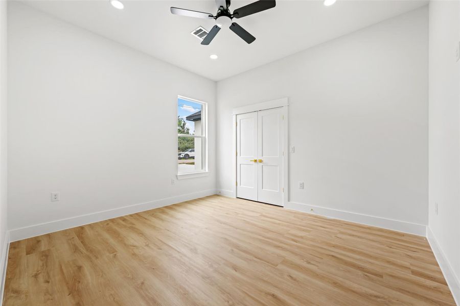Bright room featuring wood-finish flooring, white walls, and a ceiling fan with integrated lighting