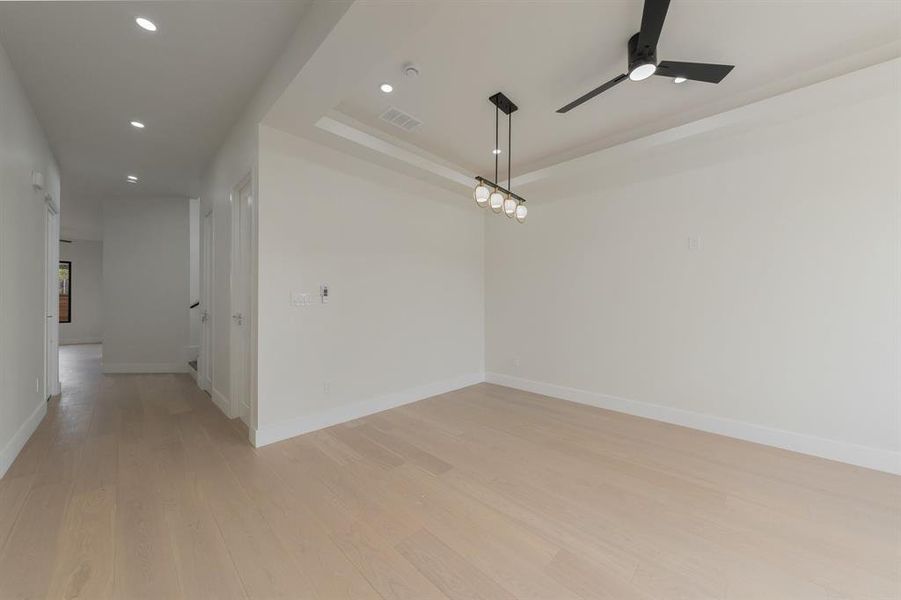 Spare room with recessed lighting, light wood-type flooring, a ceiling fan, and a raised ceiling Spare room with recessed lighting, light wood-type flooring, a ceiling fan, and a raised ceiling