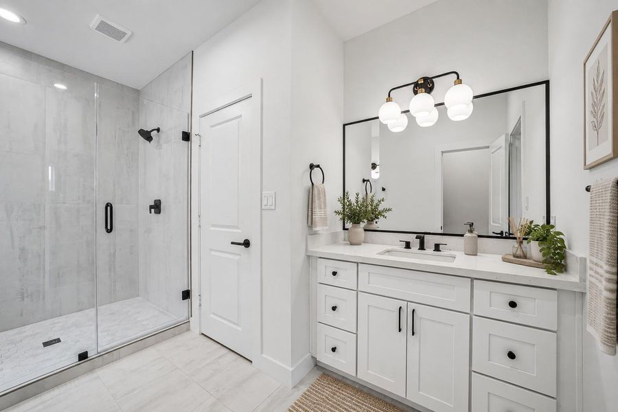 Primary Bath. Separate vanities and walk in shower with floor to ceiling tile surround.