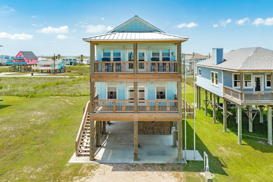 Elevated coastal home with dual covered balconies, durable metal roof, and generous under-home parking and storage, designed for easy beach living.
