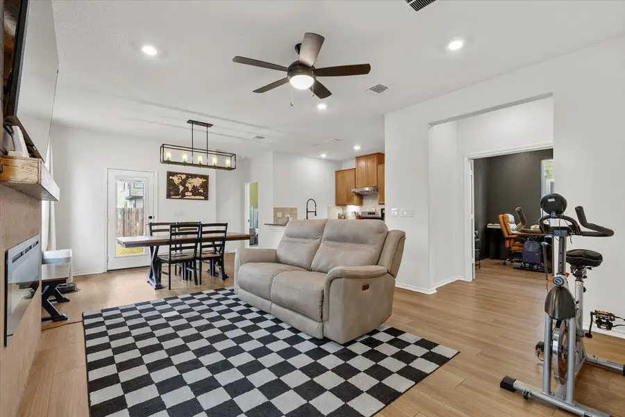 An open concept living area boasts a modern linear chandelier and ample natural light.