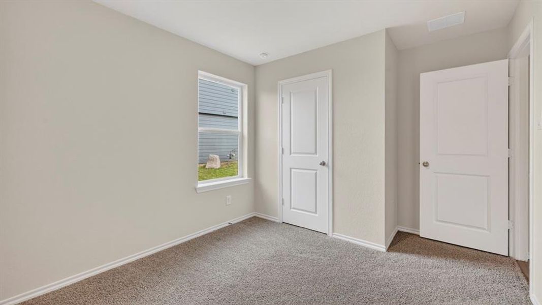 Neutral-toned room featuring a single window with white trim, two white paneled doors, and gray carpet flooring